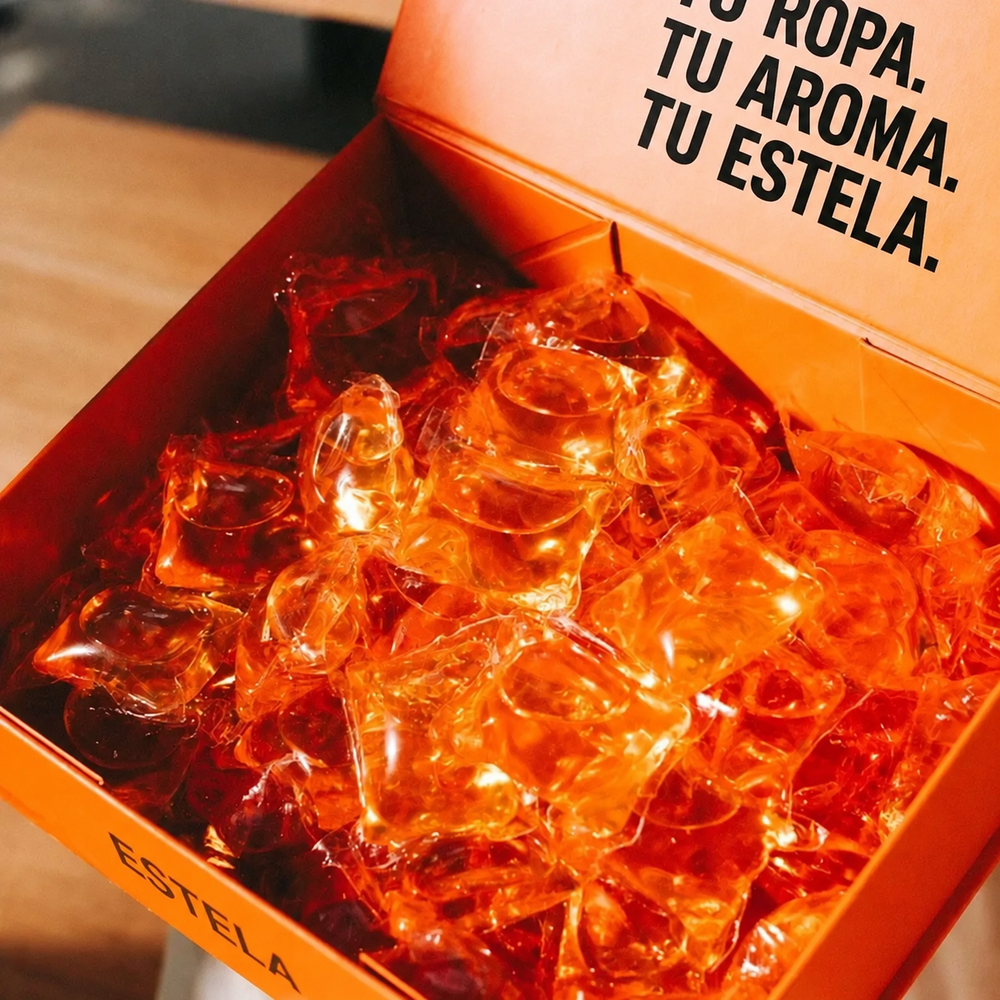 Una caja naranja abierta con cápsulas de detergente en su interior