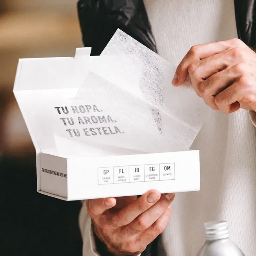 Una mano muestra una hoja para secadora sobre su caja abierta